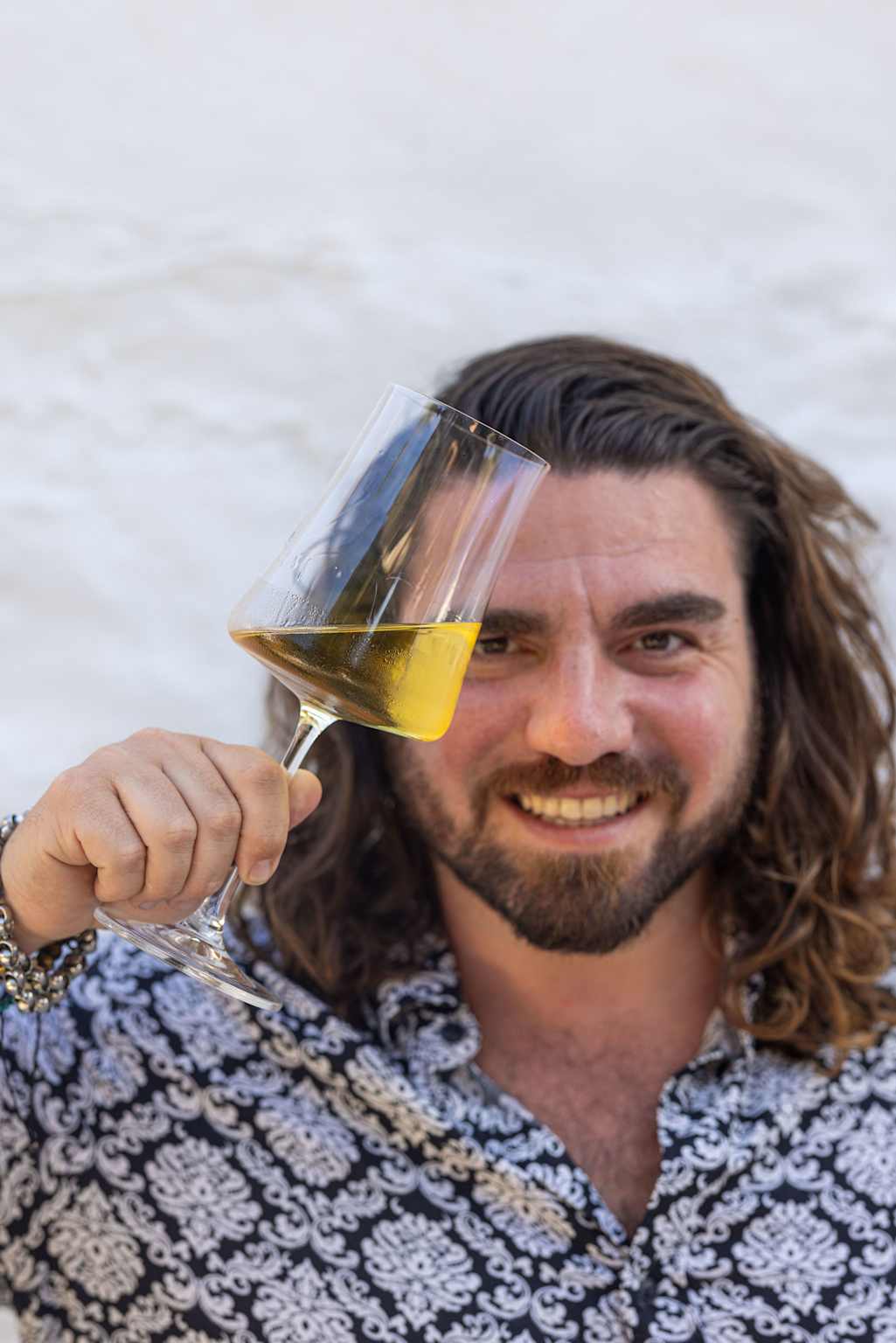 proprietario mediterraneo con calice di vino inclinato come un brindisi 